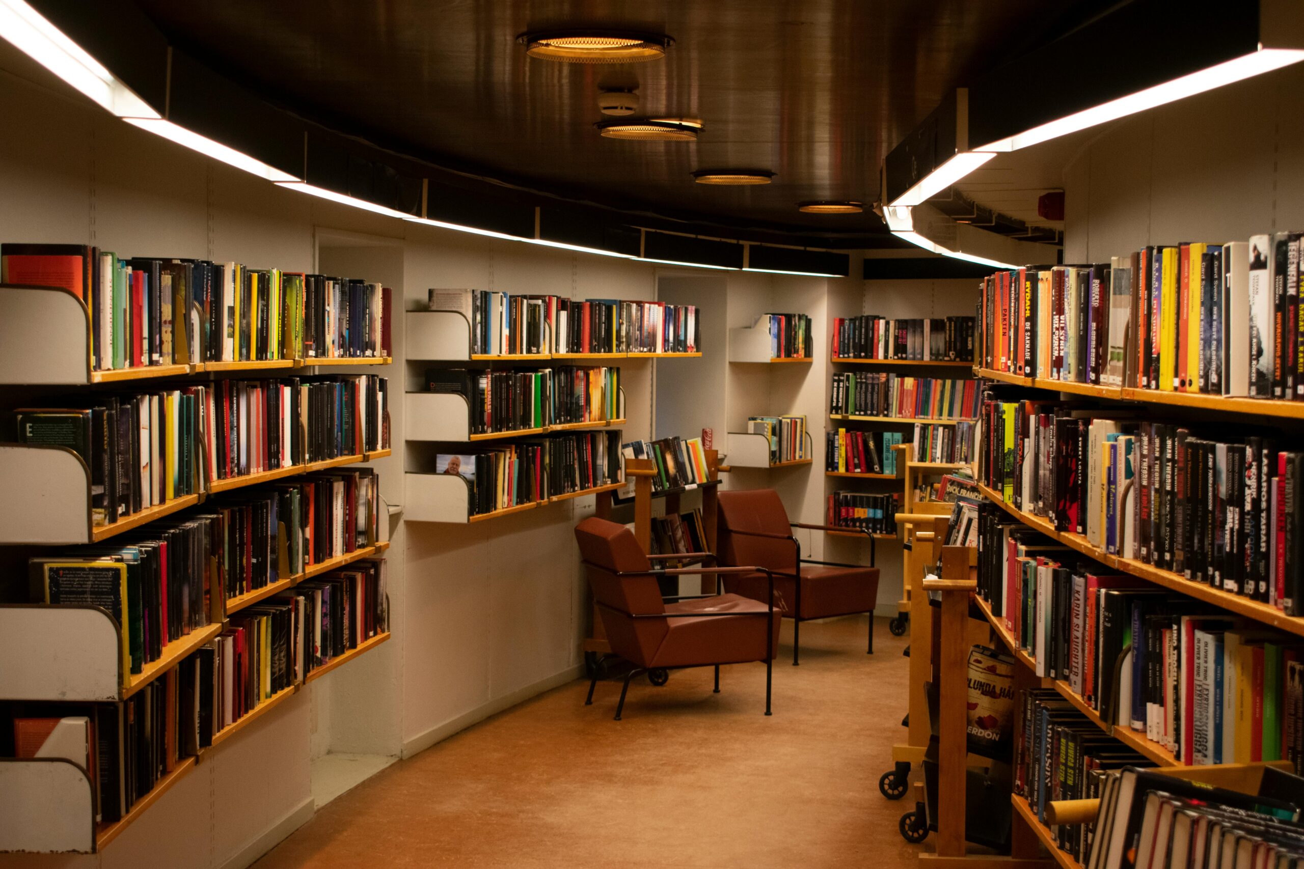 Estudiante adulto con libros y ordenador en biblioteca moderna
